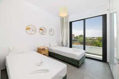 a bedroom with two beds and a large window at By The Beach - Blue Topaz Villa in Protaras