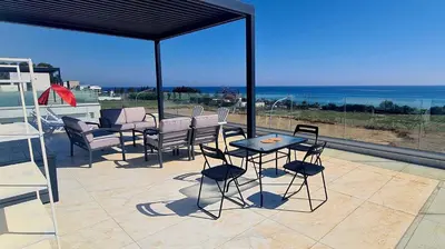 a patio with chairs and a table and a view of the ocean at By The Beach - Emerald Seaview Villa in Protaras