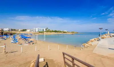 a beach with a bunch of people laying on the sand at By The Beach - Emerald Seaview Villa in Protaras