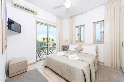 a white bedroom with a bed and a balcony at Sunrise Bay Villa #3 in Protaras