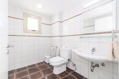 a white bathroom with a toilet and a sink at Sunrise Bay Villa #6 in Protaras