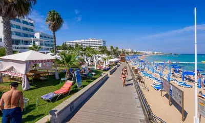 a beach with people walking down a boardwalk at Mylos Lifestyle Seaview Villa #15 in Protaras