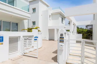 a white house with a gate and a building at Green Bay Villa #14 in Protaras