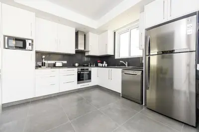 a kitchen with white cabinets and a stainless steel refrigerator at Green Bay Villa #14 in Protaras