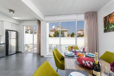 a kitchen and dining room with a table and chairs at Green Bay Villa #14 in Protaras