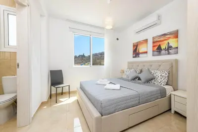 a white bedroom with a bed and a bathroom at Green Bay Villa #16 in Protaras