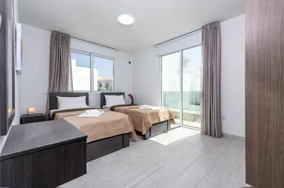 a hotel room with two beds and a large window at Green Bay Villa #17 in Protaras