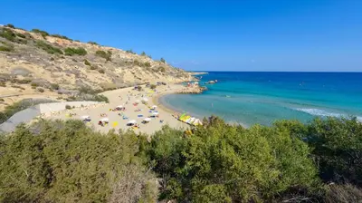 a beach with people and umbrellas and the ocean at Green Bay Villa #17 in Protaras