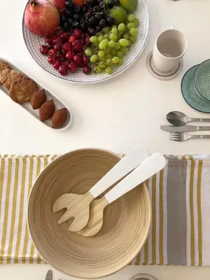 a table with two wooden spoons and a plate of fruit at Villa Greco Mare #6 in Protaras