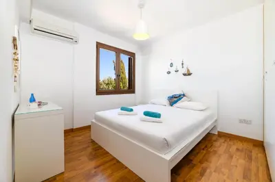 a white bedroom with a white bed and a window at Villa Greco Mare #40 in Protaras