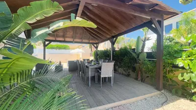 a wooden deck with a table and chairs under a pavilion at Hanns Villa in Protaras