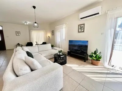 a living room with a white couch and a tv at STAY Tranquility Cove in Larnaka
