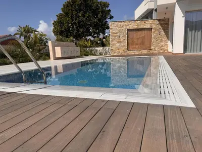 a swimming pool with a wooden deck next to a house at City Napa Seaview Villas - Villa 6 in Ayia Napa