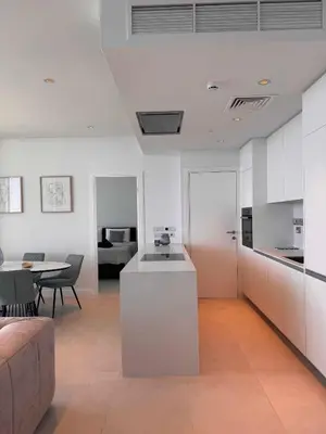 a kitchen and living room with white cabinets and a table at Ayia Napa Marina Exclusive Apartment in Ayia Napa