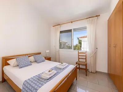 a bedroom with a bed and a window and a chair at Villa Alexandra in Protaras
