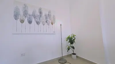 a white wall with a painting of feathers on it at STAY White Petals Apartment in Larnaka