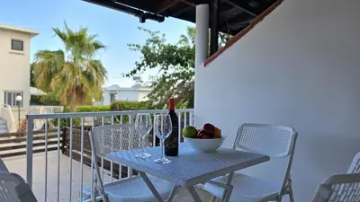 a table with wine glasses and a bowl of fruit on a balcony at STAY Blissful Apartment in Protaras