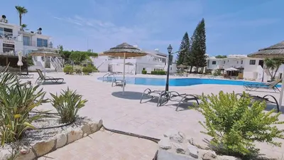 a courtyard with a pool and chairs and buildings at STAY Blissful Apartment in Protaras