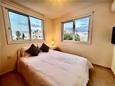 a bedroom with a white bed with two windows at KAMILA 5 in Voroklini