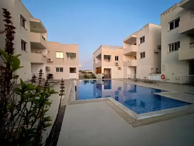 a swimming pool in the middle of two buildings at Creative 1br Pool view Apt with covered parking in Livadhia