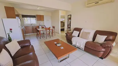 a living room with leather couches and a table at Nissi Golden Sands Privileges Apt in Ayia Napa