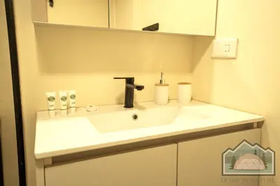 a white bathroom sink with a black faucet at Dome in Nature in Larnaka