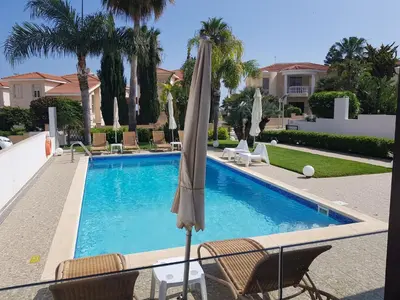 an umbrella sitting next to a swimming pool at POSEIDONIA BEACH GARDENS in Paralimni