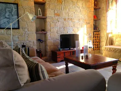 a living room with a couch and a table and a tv at Lofou Traditional Stone House in Lofou