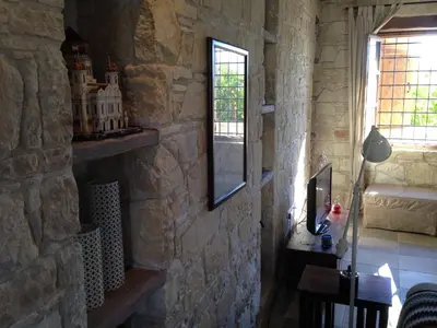 a room with a stone wall with a mirror and a table at Lofou Traditional Stone House in Lofou