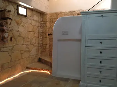 a bathroom with a white refrigerator next to a stone wall at Lofou Traditional Stone House in Lofou