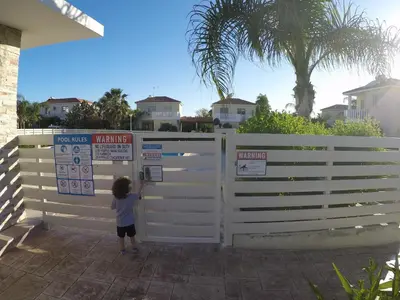 a young child standing behind a white fence at Sunrise Villa in Pervolia