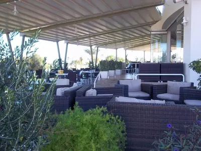 a patio with couches and chairs under a roof at Bowker Apartment in Protaras