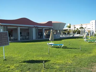 a group of chairs and umbrellas in front of a building at Bowker Apartment in Protaras