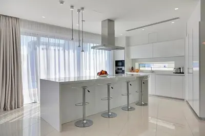 a kitchen with white cabinets and a island with bar stools at Sea Pearl Seaview Villa - Oriana in Ayia Napa