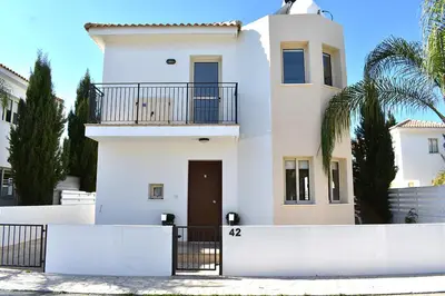 a white house with a balcony and a gate at Palm Village Escape in Protaras