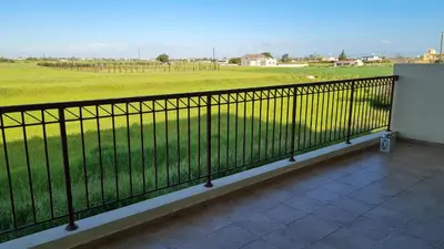 a balcony with a black fence and a field at The Olive Grove Escape, Eleonas Apts in Sotira