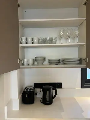 a kitchen with shelves with glasses and a tea kettle at Modern 2bed in the centre in Nicosia