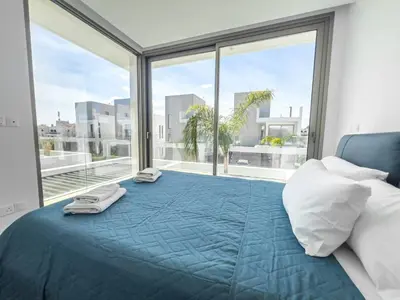 a bedroom with a large bed with a large window at Azure Vista Collection in Protaras