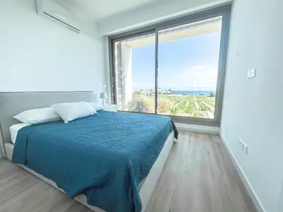 a bedroom with a blue bed and a large window at Azure Vista Collection in Protaras