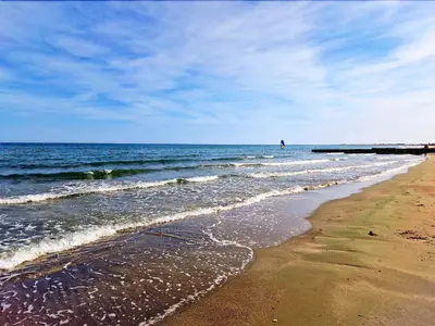 a beach with a pier and the ocean on a sunny day at The Ciao Stelio Deluxe Boutique Hotel - Adults Only in Larnaka