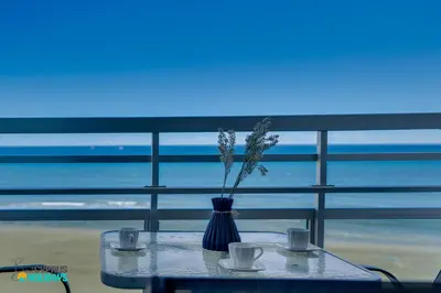 a table with two cups and a vase with flowers at Makenzy Sandy Beachfront Paradise in Larnaka