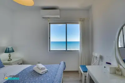 a bedroom with a bed with a view of the ocean at Makenzy Sandy Beachfront Paradise in Larnaka