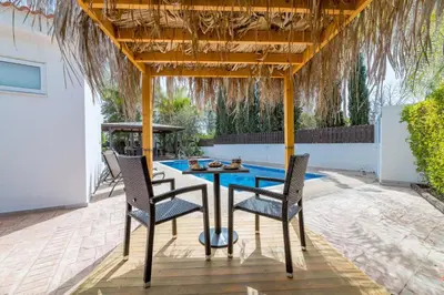 a patio with a table and chairs under a pergola at Thekla Oasis Villa in Ayia Napa