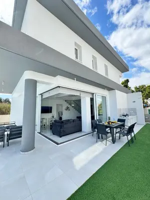 a white house with a patio with a table and chairs at Protaras Rustic Paradise Luxury Villa 1 in Paralimni