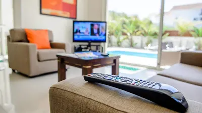 a remote control sitting on the arm of a couch in a living room at Kapparis Holiday Villa 018 in Protaras