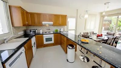 a kitchen with wooden cabinets and a counter top at Kapparis Holiday Villa 018 in Protaras