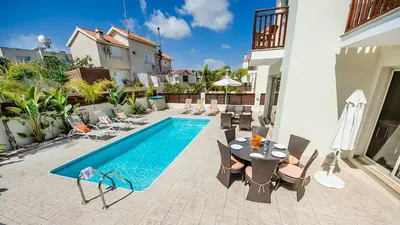 a swimming pool with chairs and a table next to a house at Kapparis Holiday Villa 018 in Protaras