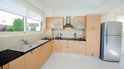 a kitchen with wooden cabinets and a stainless steel refrigerator at Pernera Holiday Villa 015 in Protaras