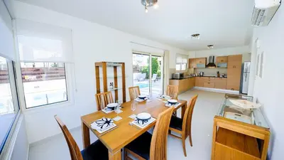 a kitchen and dining room with a wooden table and chairs at Pernera Holiday Villa 015 in Protaras