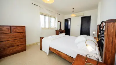 a bedroom with a white bed and a wooden dresser at Pernera Holiday Villa 015 in Protaras
